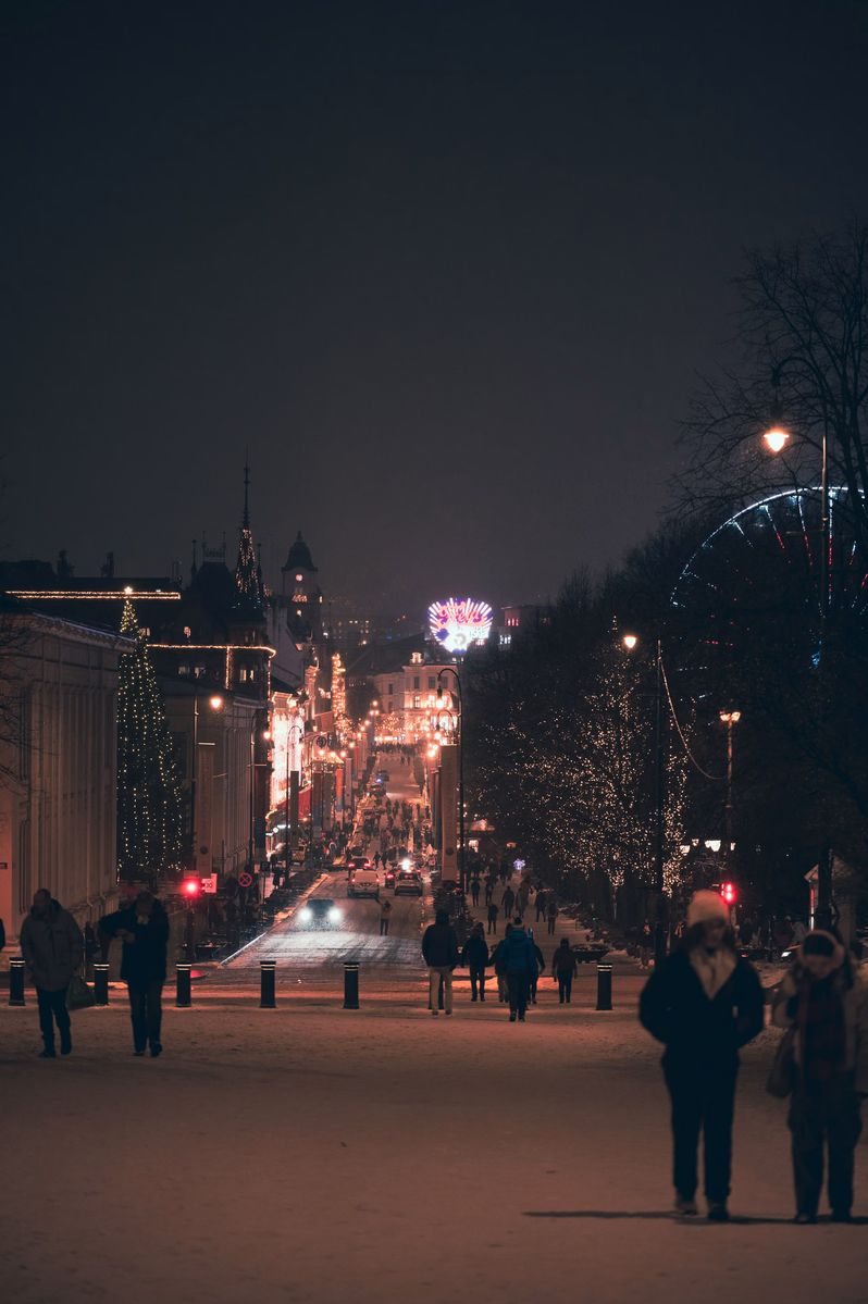 Die Karl Johans gate im Advent am Abend, mit Lichtern und einem Riesenrad im Hintergrund