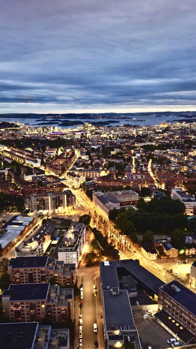 Oslo bei Nacht von oben, mit beleuchteten Straßen und dem Fjord im Hintergrund